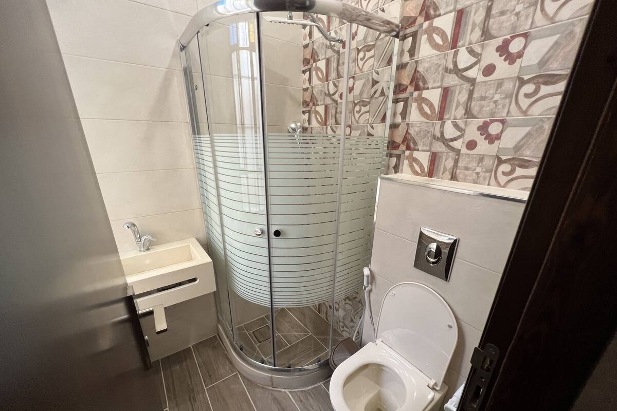 Un baño moderno con ducha acristalada, inodoro y lavabo.