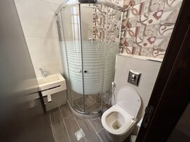 Un baño moderno con ducha acristalada, inodoro y lavabo.