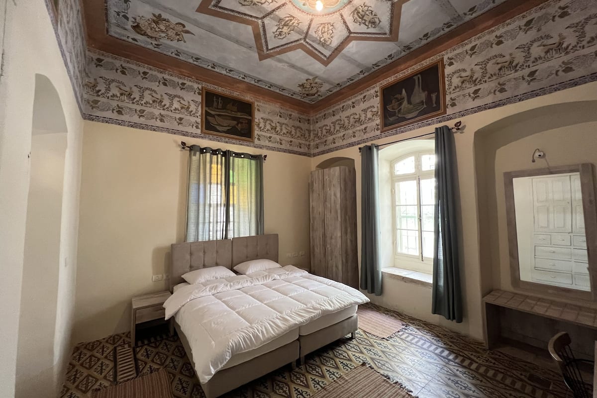 Un dormitorio con una cama grande, un armario de madera, baldosas de suelo con diseño y techo decorativo.
