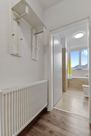 Un baño moderno con un radiador blanco, suelo de madera, una ventana con vistas y un inodoro.