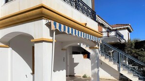 A building with a white facade, blue and yellow trim, and a staircase leading to a balcony. - Apartment in Vera Playa near the Beach (Vera Playa)