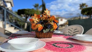 A table set with white plates, a basket of flowers, and a patterned tablecloth. - Apartment in Vera Playa near the Beach (Vera Playa)