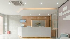 A modern reception area with a white reception desk, a mounted television, and a wooden accent wall. - Greentree Inn Hefei Binhu Century City Binhu Hospital (Hefei)