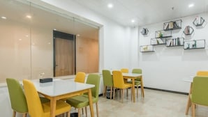 A conference room with a white table and chairs, a glass partition, and a wall with shelves holding books and decorative items. - Greentree Inn Hefei Binhu Century City Binhu Hospital (Hefei)