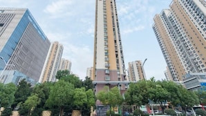 A high-rise building with multiple floors, surrounded by other tall buildings and trees. - Greentree Inn Hefei Binhu Century City Binhu Hospital (Hefei)