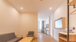 A modern, well-lit room with a wooden floor, a sofa, a small table, and a TV mounted on the wall. - Greentree Inn Hefei Binhu Century City Binhu Hospital (Hefei)