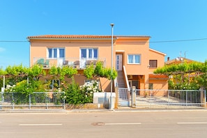 A two-story building with a balcony, a staircase, and a gated entrance.