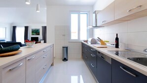 A modern kitchen with light-colored cabinets, a stainless steel sink, and a window providing natural light.