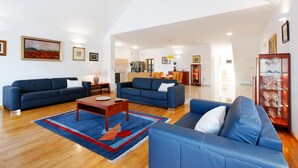 A spacious living room with two blue sofas, a coffee table, and a rug.