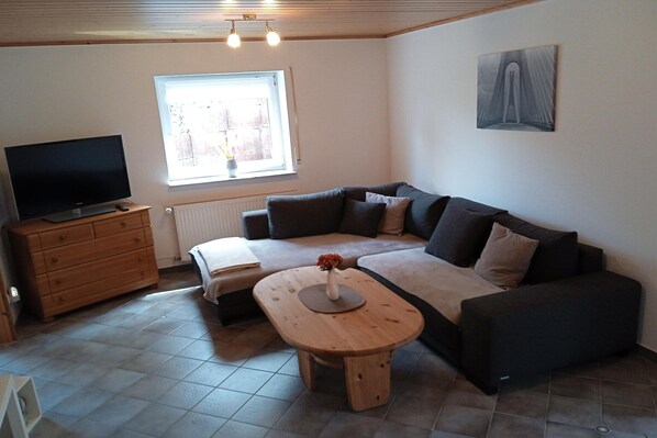 A living room with a sofa, a coffee table, a TV, and a window with a view.