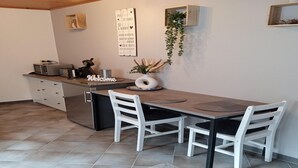 A modern kitchen with a dining area, featuring a built-in oven, a coffee machine, and a small plant on the counter. - Tranquil Getaway in Scenic Roes (Roes)