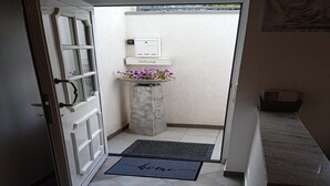 A hotel entrance with a door, a doormat, a small planter with flowers, and a wall-mounted light switch. - Tranquil Getaway in Scenic Roes (Roes)