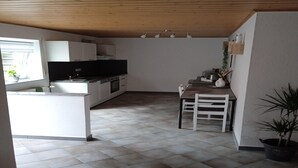 A compact kitchen with white cabinets, a black countertop, and a dining area with a table and chairs. - Tranquil Getaway in Scenic Roes (Roes)