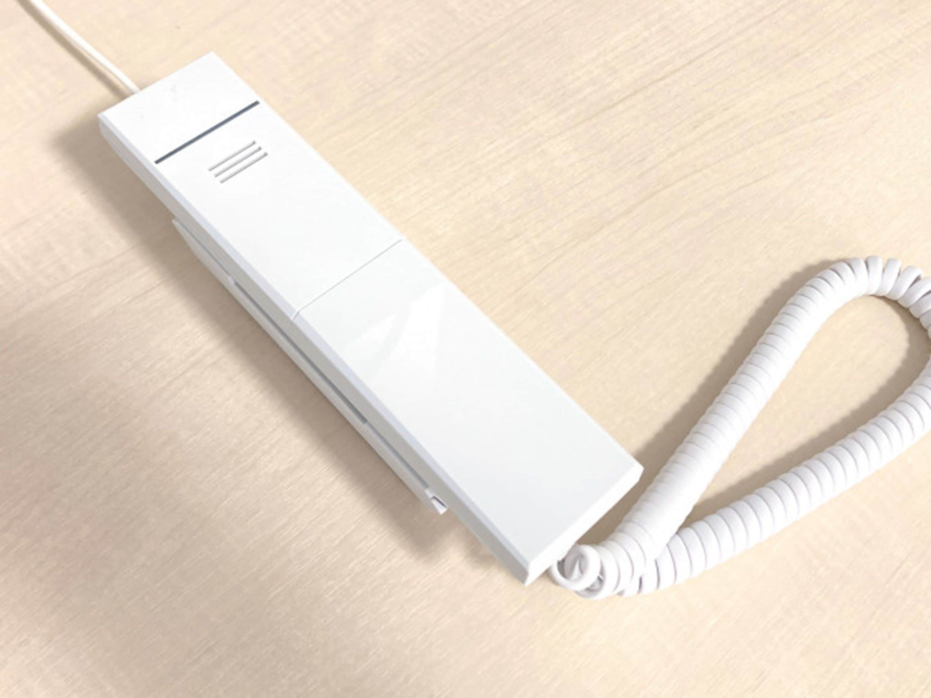 Un dispositivo blanco y rectangular con cable, y un cable enrollado sobre una superficie de madera.