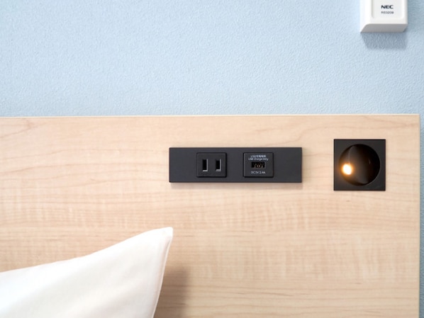 Una regleta de pared con puerto USB y toma de corriente, un foco empotrado y un interruptor de pared blanco etiquetado "NEC".