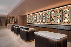 A modern hotel lobby with a reception desk, a wall of circular light fixtures, and a decorative mirror display. - The Perfect Place to Stay! Close to Miami Art Museum, Pet Friendly, Free Shuttle (Miami)