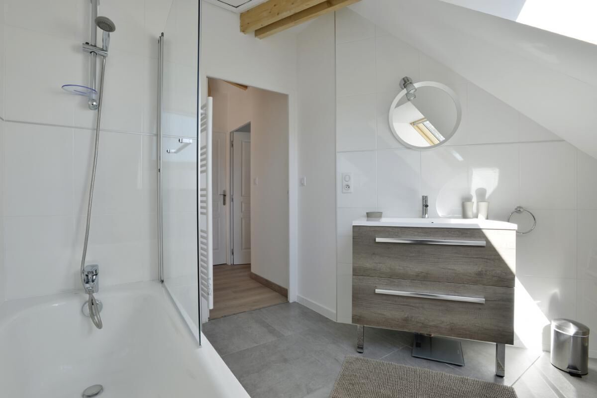 Une salle de bain moderne avec une douche, un meuble-lavabo avec un miroir et un placard en bois.