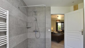 A modern bathroom with a shower, tiled walls, and a visible toilet. - Le Clos du Héron Perché (HOUDETOT)