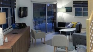 A modern living room with a wooden ceiling, a sofa set, a coffee table, and a TV mounted on the wall. - Le Clos du Héron Perché (HOUDETOT)