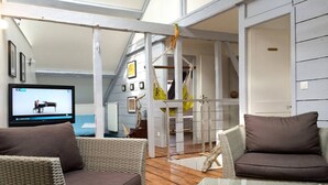 A cozy room with wicker furniture, a glass table, and a television displaying a piano. - Drakkar - Fecamp - City Break (FECAMP)