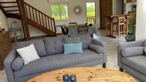 A living room with a grey sofa, a wooden coffee table, and a staircase. - Jade - Angerville LA Martel (ANGERVILLE LA MARTEL)