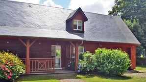 A wooden house with a porch, a small attached shed, and a well-maintained lawn. - Jade - Angerville LA Martel (ANGERVILLE LA MARTEL)