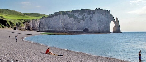 Ein Kiesstrand mit weißen Klippen im Hintergrund.