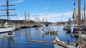 A marina with multiple sailing boats docked, a small rowboat in the foreground, and a building with a tower in the background. - La Corderie - Fecamp (FECAMP)
