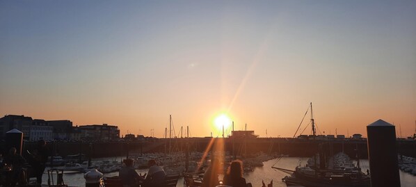 A marina with boats docked, a sunset in the background, and buildings along the waterfront. - La Corderie - Fecamp (FECAMP)