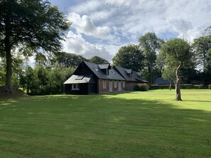 Set amidst a serene lawn, this charming house features a two-story design with a brick exterior and a small window on the side.