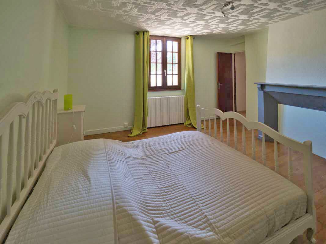 Une chambre avec un lit simple, un radiateur, une fenêtre avec des rideaux et une porte.