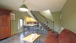 Un vaste espace de vie comprenant un escalier, une table à manger et un canapé rouge.