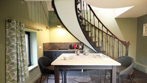 Un espace repas comprenant une table, des chaises et un escalier en colimaçon.
