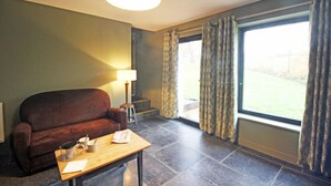 Une pièce avec un canapé, une table avec une lampe et une grande fenêtre avec des rideaux.