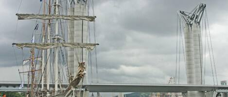 Un barco mercante alto llamado 'ANTIGUA' atracado en un puerto con un puente al fondo.