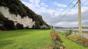 A grassy field with a white cliff and a body of water in the background.