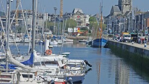 A marina with multiple boats docked, a prominent church tower in the background, and a construction crane visible.