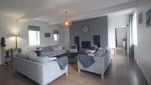 A modern living room with a grey sofa set, a coffee table, and a hanging light fixture.
