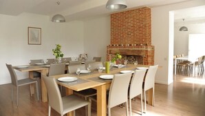 A dining area with a brick fireplace, wooden tables, and modern chairs.