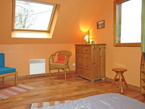 Relax in this inviting room with a sloped ceiling, a dresser, a wicker chair, and a blue sofa.
