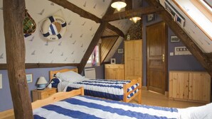 Une chambre avec deux lits, des poutres en bois, un plafond mansardé et un gilet de sauvetage accroché au mur.