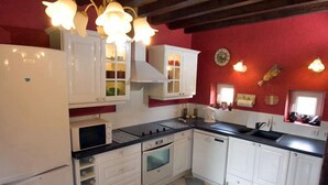 Une cuisine avec des armoires blanches, un comptoir noir, un four encastré et un four à micro-ondes. On y trouve des luminaires suspendus et une fenêtre donnant sur l’extérieur.