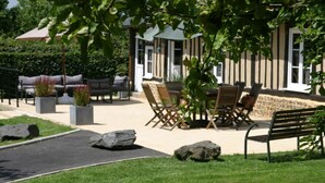 Un espace extérieur aménagé avec des tables et des chaises, entouré de verdure et de rochers.