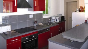 Una cocina con armarios rojos, una campana extractora negra, horno empotrado y encimera gris.