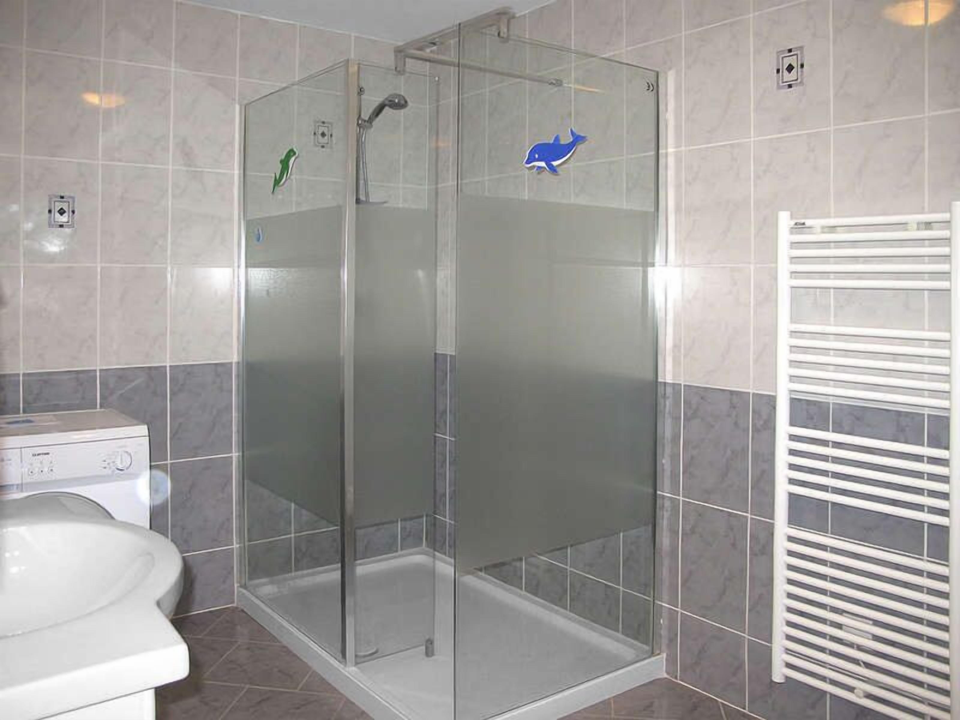 A modern bathroom with a glass-enclosed shower, a white sink, and a towel rack.