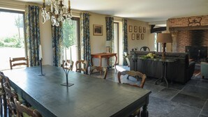 Un espace repas comprenant une grande table et des chaises, un lustre et une cheminée.