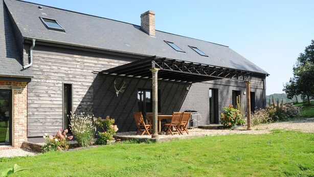 Une maison dotée d’un patio couvert, d’une façade en briques et d’une cour gazonnée.