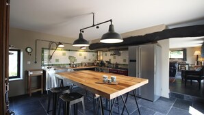 Une cuisine moderne dotée d’un îlot central, de tabourets de bar, de luminaires suspendus et offrant une vue sur l’espace de vie.