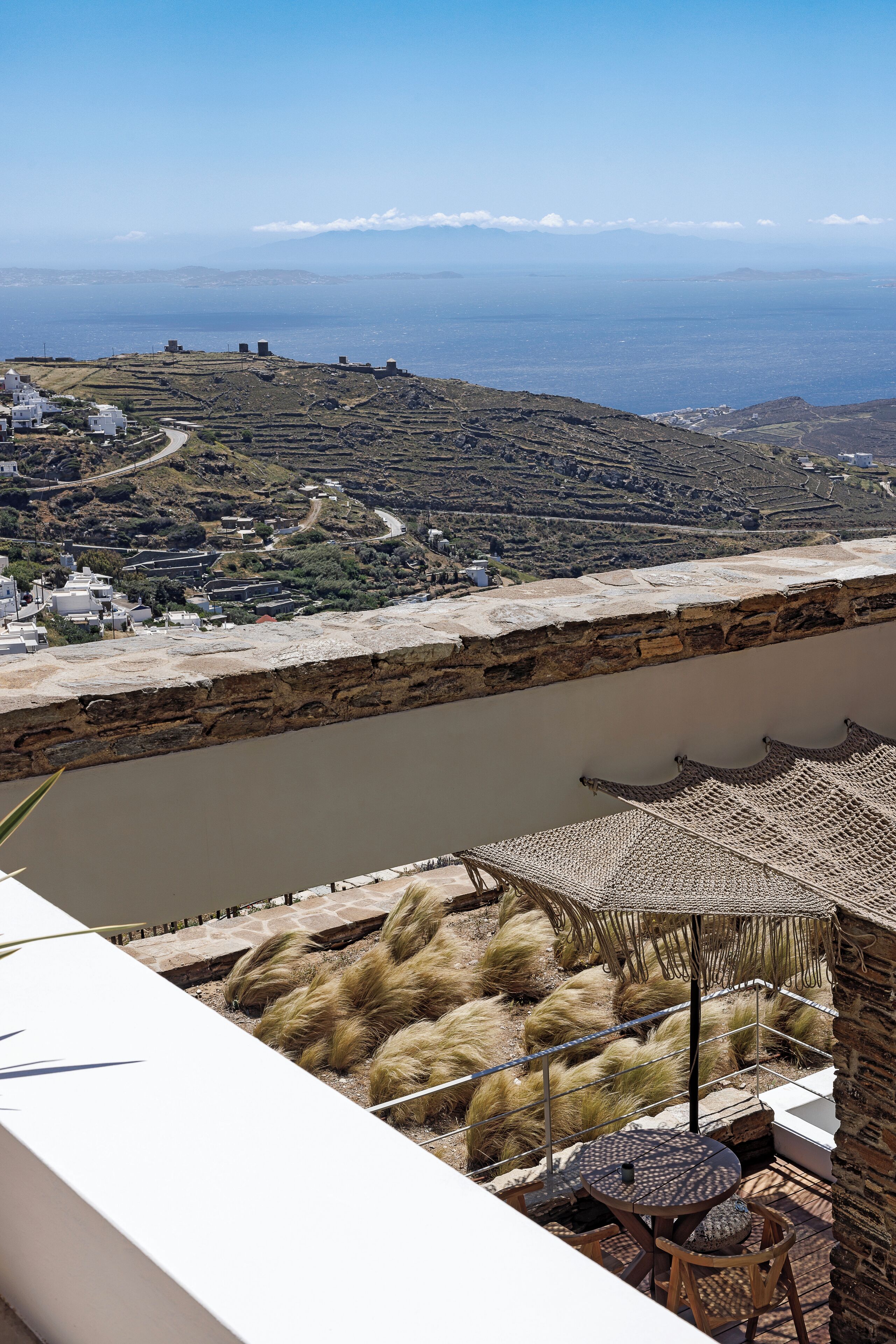 Una terraza con vistas a un río y montañas distantes, que incluye una mesa y sillas.