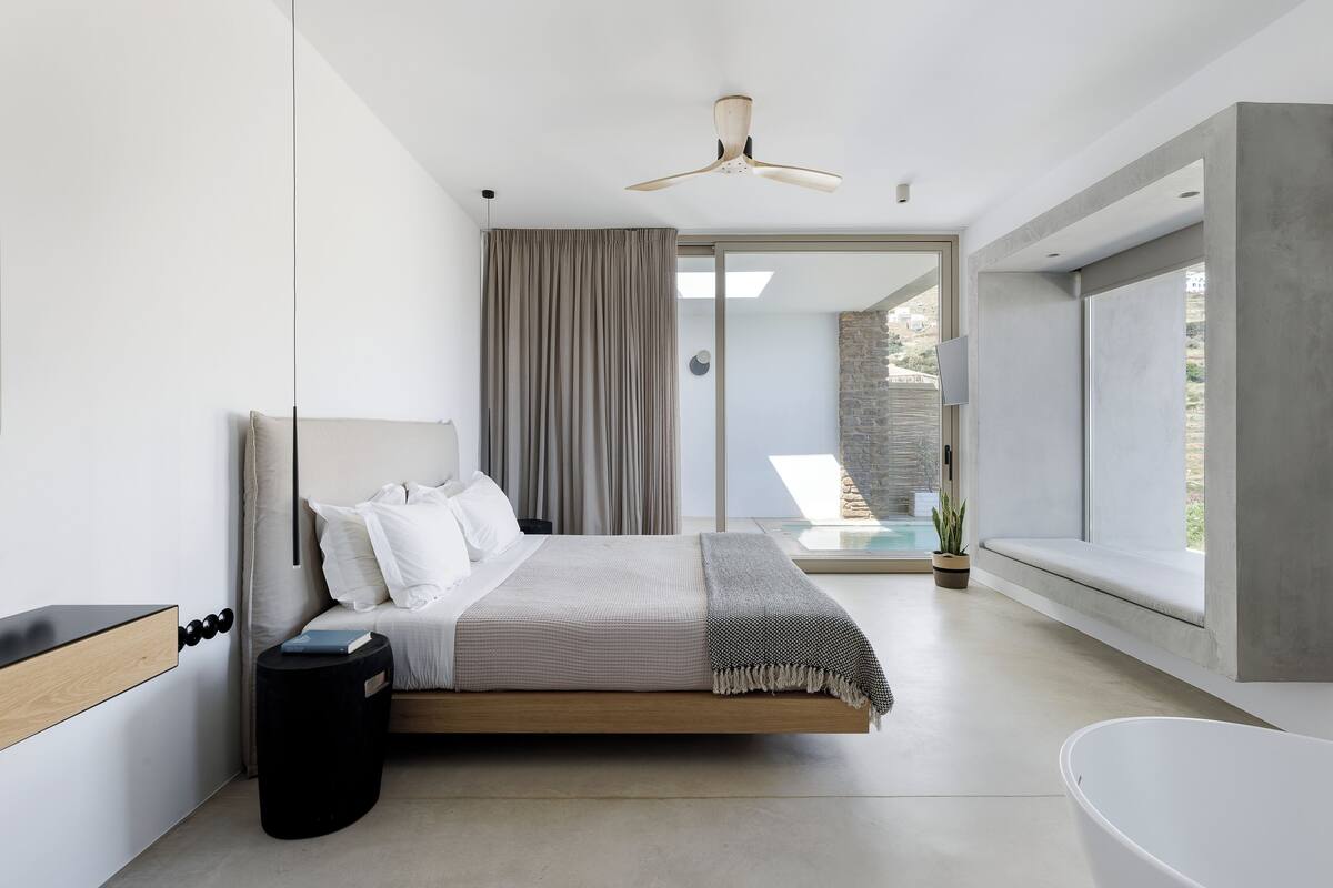 Un dormitorio moderno con una cama, una mesita de noche, un ventanal y vistas al exterior.